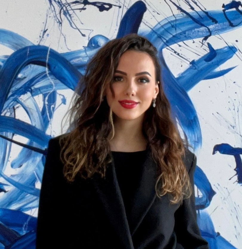 Zhanna Mezhenska standing in front of her blue abstract painting