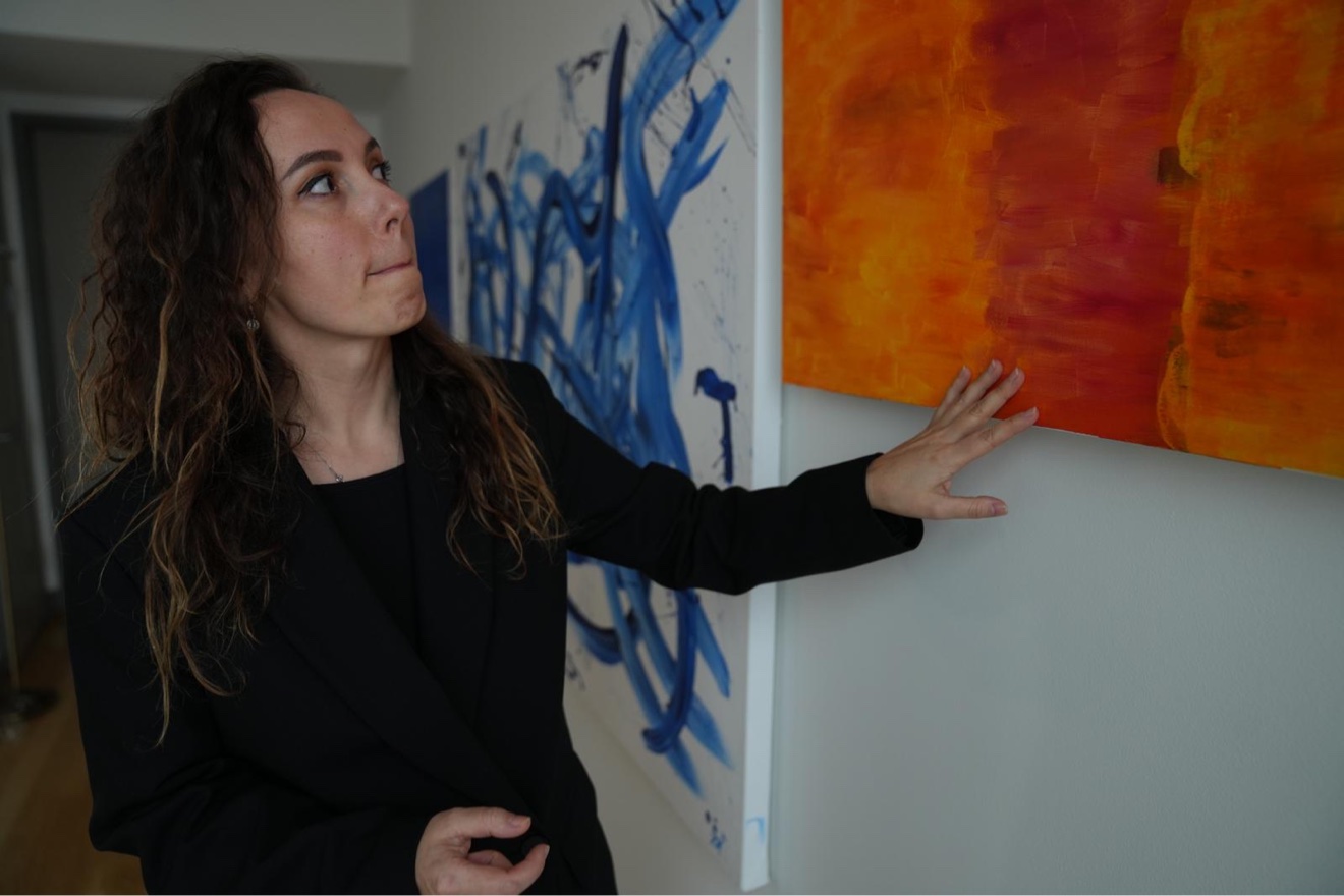 Zhanna touching an orange painting while reading its energy